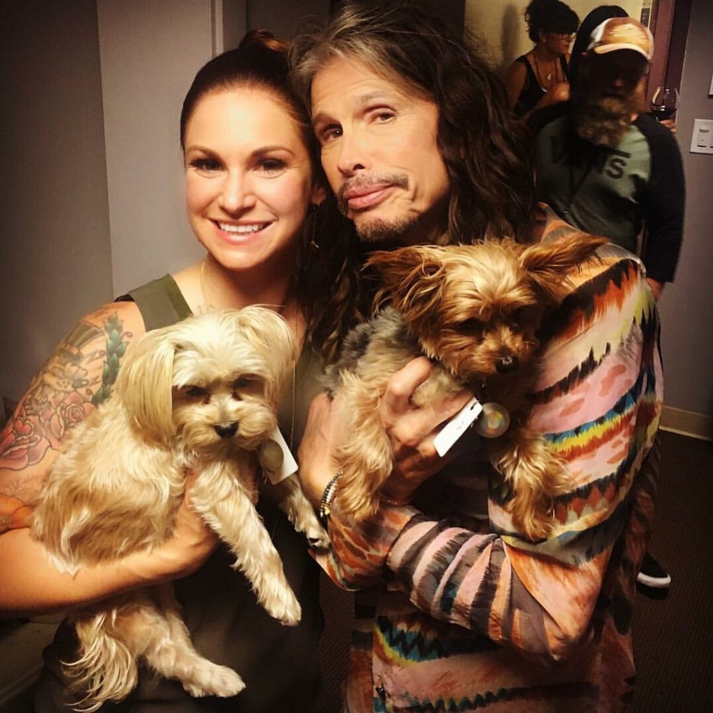 Dog Trainer Cora Wittekind smiles with Steven Tyler and two dogs