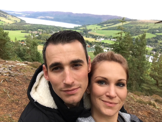 Cora Wittekind and Sid Williams smile at camera with the Scottish Highlands in background